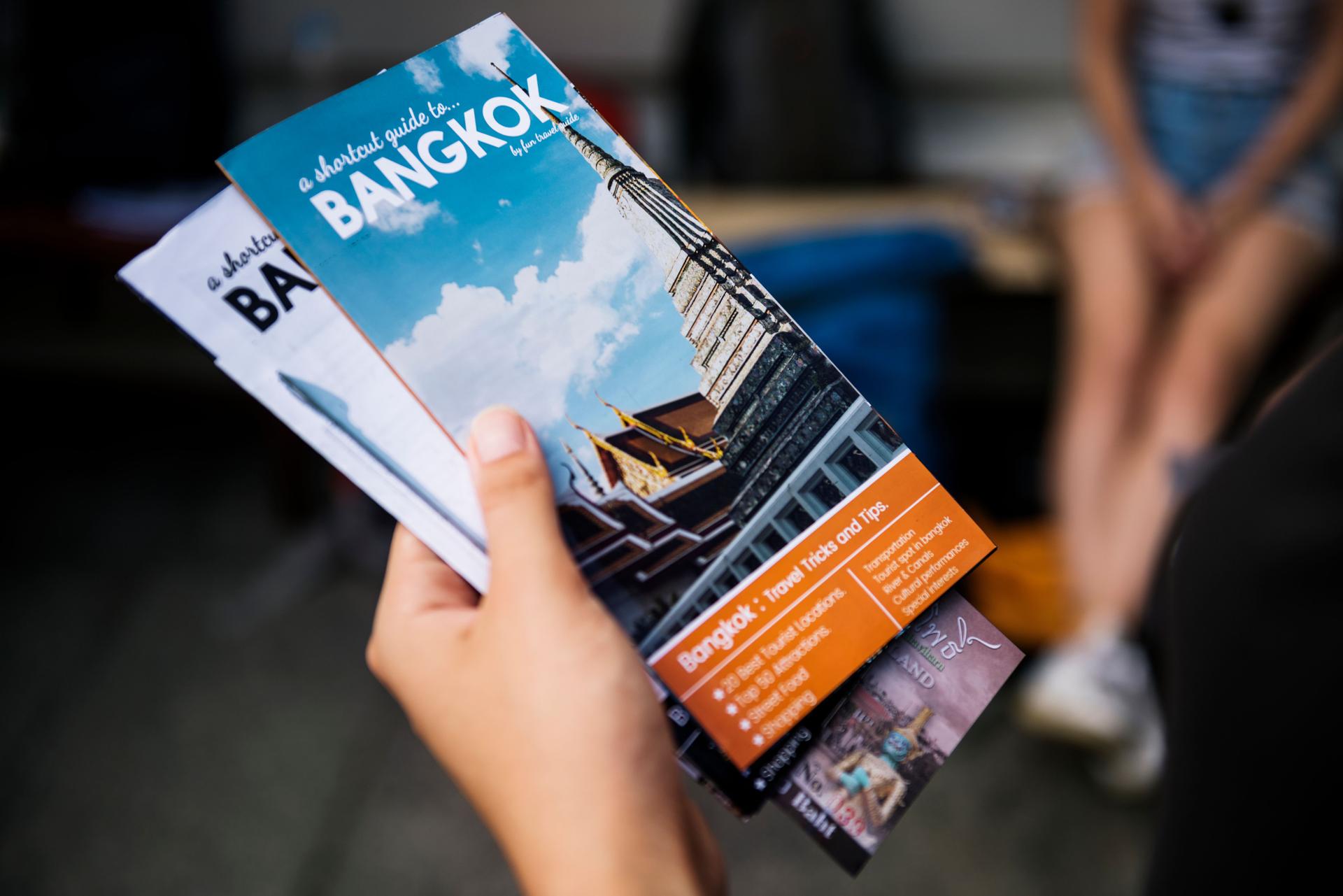 Primer plano de la mano que sostiene el folleto de guía de viajes Bangkok